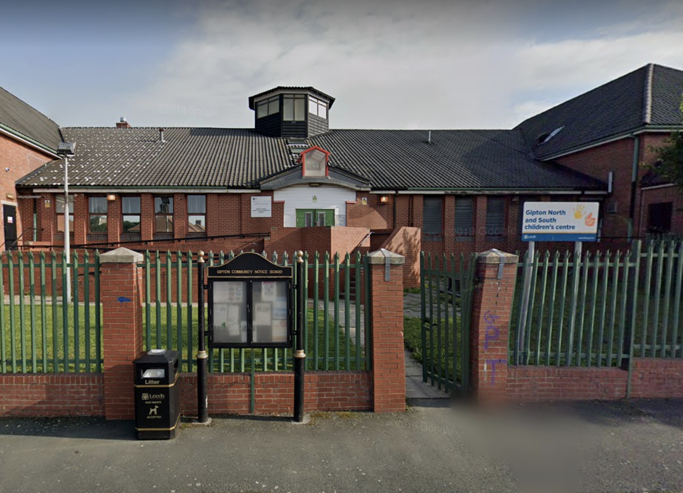 A photograph of the Henry Barran Community Centre, Gipton from outside the front. It is a one-storey brick building with a fence out front and a large sloping roof.